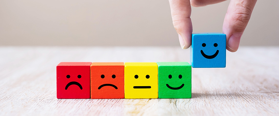 Emotion face symbol on yellow wooden cube blocks. 