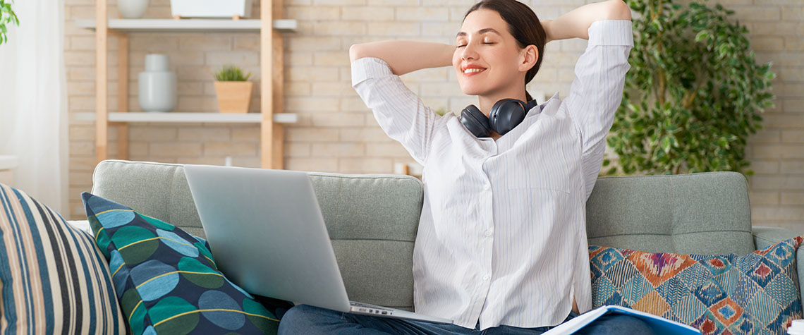 Adult woman relaxing at home on sofa with laptop researching how to microdose shrooms.