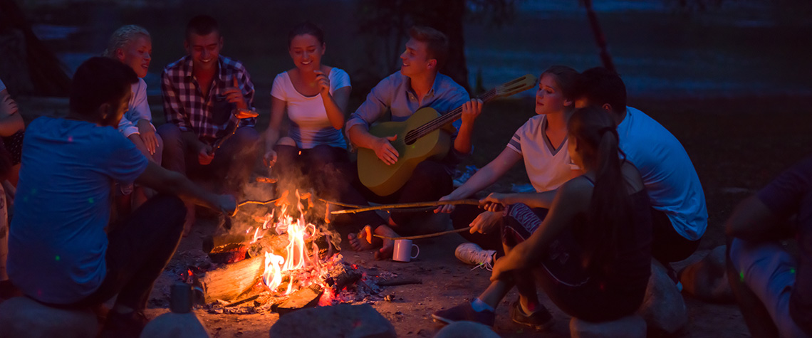 young friends relaxing around campfire. what are the effects of magic mushrooms on the body? How long does it take for mushrooms to take effect?