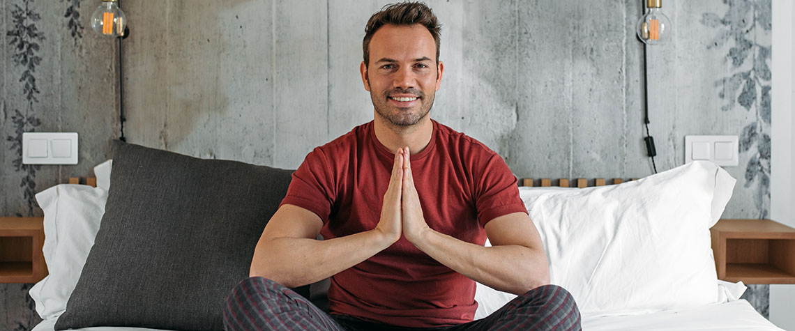 man sitting in lotus position on bed meditating. buy penis envy shrooms online in canada.